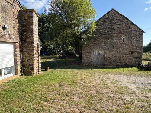 an old brick building with a door in the yard at Location de vacances brocéliandes in Maxent