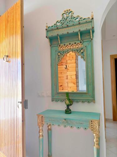 a blue table with a mirror on a wall at Dar Emna in El Guecheïne