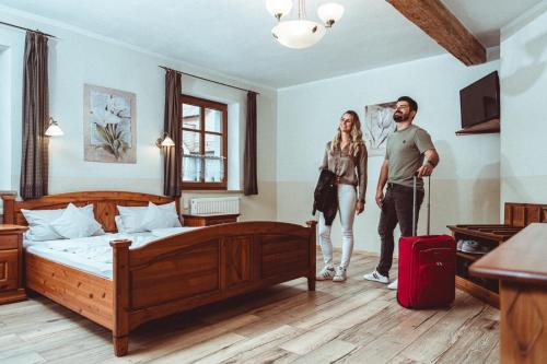 a man and woman standing in a hotel room with a suitcase at Landhotel Kahrmühle in Pressath