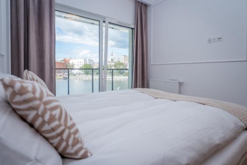 Un dormitorio con una cama y una ventana grande en Bulwary nad Odrą Apartments z widokiem na rzekę Odrę i prywatnym miejscem parkingowym, en Szczecin