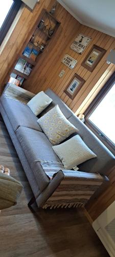 a couch with pillows sitting on a wooden floor at Refugio Verde Apartamento entero con entrada independiente in Puerto Varas