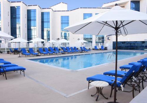 a swimming pool with blue chairs and an umbrella at Montego Bay Resort Casino by Peppermill Resorts in West Wendover
