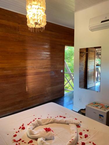 a bedroom with a bed with red rose petals on it at Pousada Kalango in Barra Grande