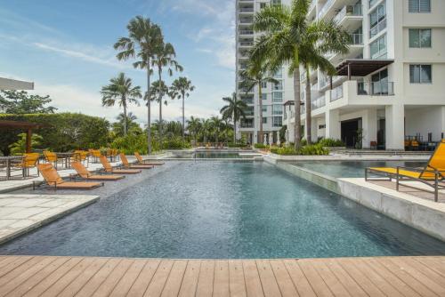 a pool with chairs and palm trees in a building at 2br Apartamento con Vista al Mar Ph Rio Mar T1-11A in San Carlos