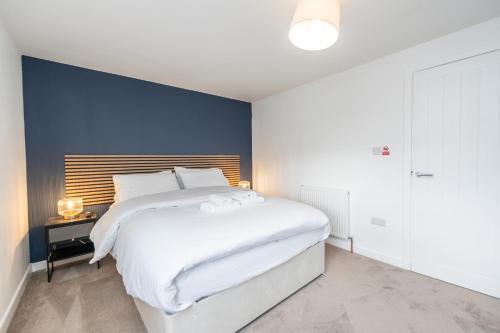 a bedroom with a large white bed and a blue wall at The Gordon Vacant Nests Heart Of Aberdeen in Aberdeen