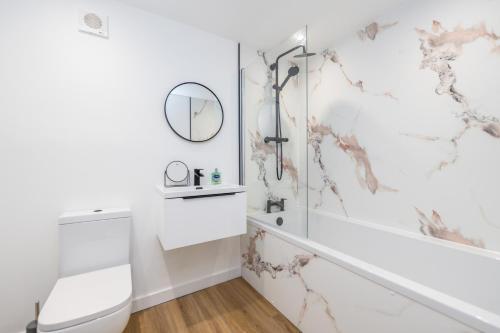 a white bathroom with a white tub and a mirror at The Gordon Vacant Nests Heart Of Aberdeen in Aberdeen
