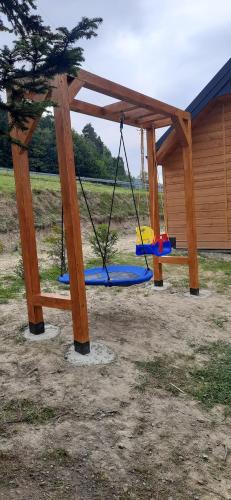 a swing set in a park with a wooden structure at Domek pod Skiełkiem in Łukowica