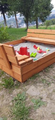 a wooden sandbox with toys in it in the grass at Domek pod Skiełkiem in Łukowica