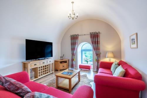 a living room with two red couches and a tv at The Highland Club in Fort Augustus