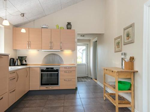 a kitchen with wooden cabinets and a table at Stylish Retreat by Kvie Lake - By Traum Ferienwohnungen in Ansager