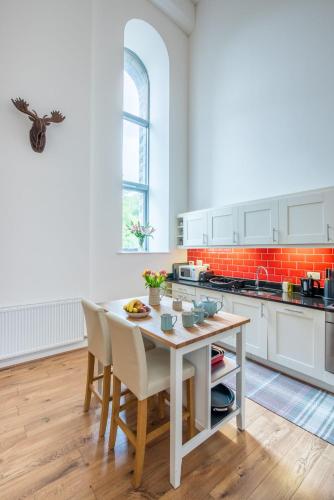 a kitchen with white cabinets and a table and chairs at The Highland Club in Fort Augustus