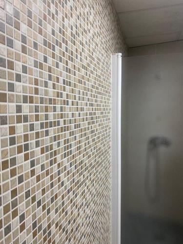 a bathroom with a shower and a tiled wall at Costa Sun Apartment in Calella