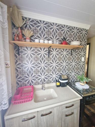 a kitchen with a sink and a patterned wall at Pousada Justi Oliveira in Louro Müller