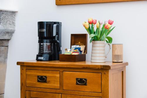 a table with a coffee maker and a vase of flowers at The Highland Club in Fort Augustus
