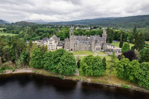 an aerial view of a castle with a lake at The Highland Club in Fort Augustus