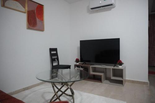 un soggiorno con tavolo in vetro e TV di Les muguets de chaville a Abidjan