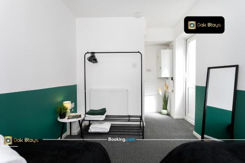 a room with a mirror and a green wall at Quick Deals l 5 Bedroom l Sleeps 10 l Parking l Ideal for Groups l Oak Stays Short Lets & Serviced Accommodations in Churchdown