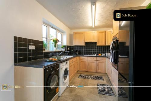 a kitchen with a washer and dryer in it at Quick Deals l 5 Bedroom l Sleeps 10 l Parking l Ideal for Groups l Oak Stays Short Lets & Serviced Accommodations in Churchdown