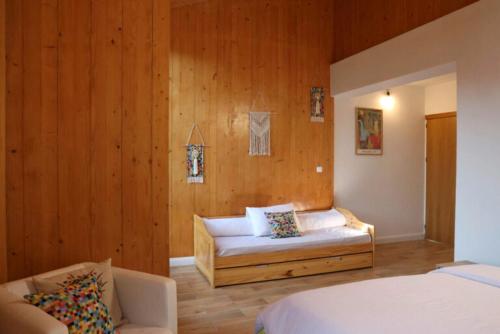 a bedroom with a bed and a couch and wooden walls at Centrul 3H in Sub Piatra
