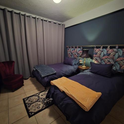 a bedroom with two beds and a chair at Bekk-bur in Potchefstroom
