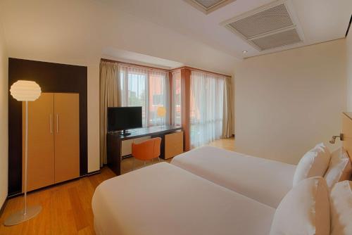 a bedroom with a bed and a desk with a television at NH Milano 2 Residence in Segrate