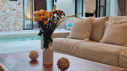a vase with flowers on a table in a living room at Santi Tara Villas in Amphoe Koh Samui