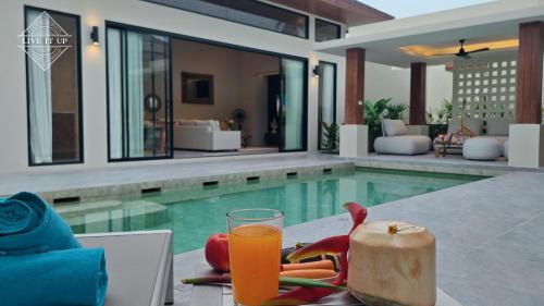 a glass of orange juice sitting on a table next to a swimming pool at Santi Tara Villas in Amphoe Koh Samui