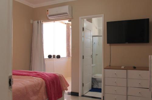 Un dormitorio con una cama y un televisor y una ventana. en Quartos na linda casa de Atalaia, en Aracaju