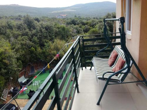 a porch with a swing and a chair on a balcony at Bigova Bay Apartments 2 in Bigovo