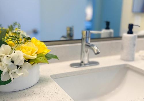 a bathroom sink with a vase of flowers on a counter at Cozy&Stylish DT Alhambra Living walk to Starbucks in Alhambra