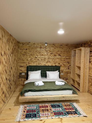 a bedroom with a bed with a wooden wall at ECHIVITI Cottages in Abastumani in Abastumani