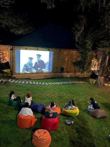 a group of people sitting in the grass watching a movie at ECHIVITI Cottages in Abastumani in Abastumani