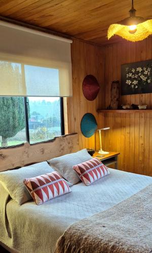 a bedroom with a bed with two pillows and a window at Hostal Boutique El Vergel Azul in Castro