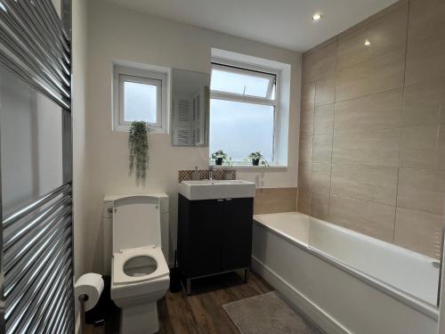 a bathroom with a tub and a toilet and a sink at 3 Bedroom modern house 15 min to tube, shops near by in Finchley