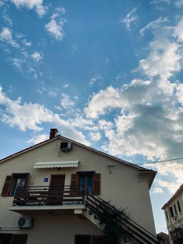 a white house with a balcony and a cloudy sky at The Village View Apartment in Višnjan