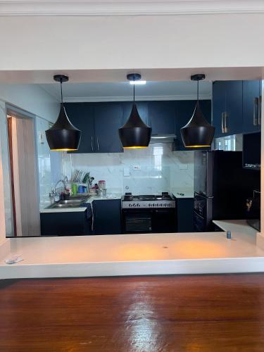 a kitchen with blue cabinets and black appliances at Spring den apartments in Rungiri