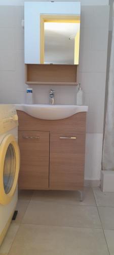 a bathroom with a sink and a washing machine at Cosy guest house with private yard in Saronida