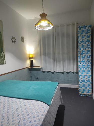 a bedroom with a bed with a blue sheet on it at Casa Aloha Barra in Maricá