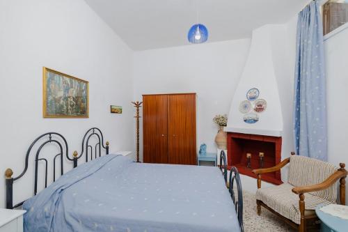 een slaapkamer met een bed en een stoel en een open haard bij Statis House in Lardos