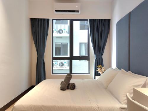 a teddy bear sitting on a bed in front of a window at Vetro11 Beside QEH1 by JUNE Homestay in Kota Kinabalu