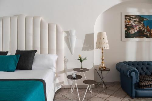 a bedroom with a bed and a blue chair at Hotel Eden Roc in Positano