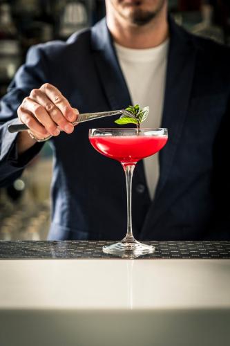 a man is stirring a red drink in a martini glass at Hotel Eden Roc in Positano