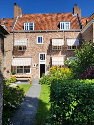 an old brick house with a garden in front of it at Chambre d'hote à Middelburg in Middelburg