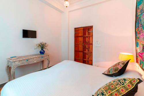 a white bedroom with a bed and a desk at Lake Pichola Hibiscus Hotel in Udaipur