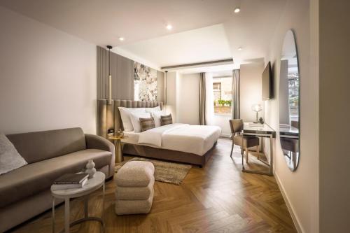 a bedroom with a bed and a couch and a desk at Boutique Hotel Mauro in Poreč