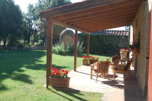a wooden pergola with chairs and a table in a yard at Agriturismo San Ansanino- Piscina con spiaggia-Aria condizionata in Pari