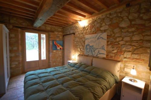 a bedroom with a large bed in a stone wall at Agriturismo San Ansanino- Piscina con spiaggia-Aria condizionata in Pari