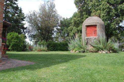a red door in a stone structure in a yard at Agriturismo San Ansanino- Piscina con spiaggia-Aria condizionata in Pari