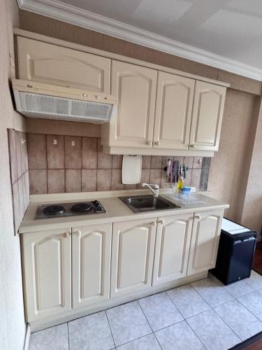 a kitchen with white cabinets and a sink at Torremolinos departamentos in Temuco