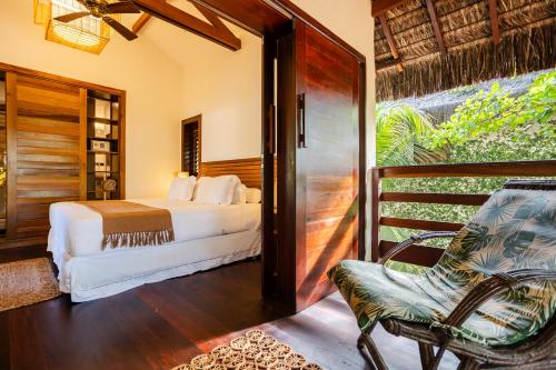 a bedroom with a bed and a chair and a balcony at Aldeia Jericoacoara - Suites Privativas in Jericoacoara